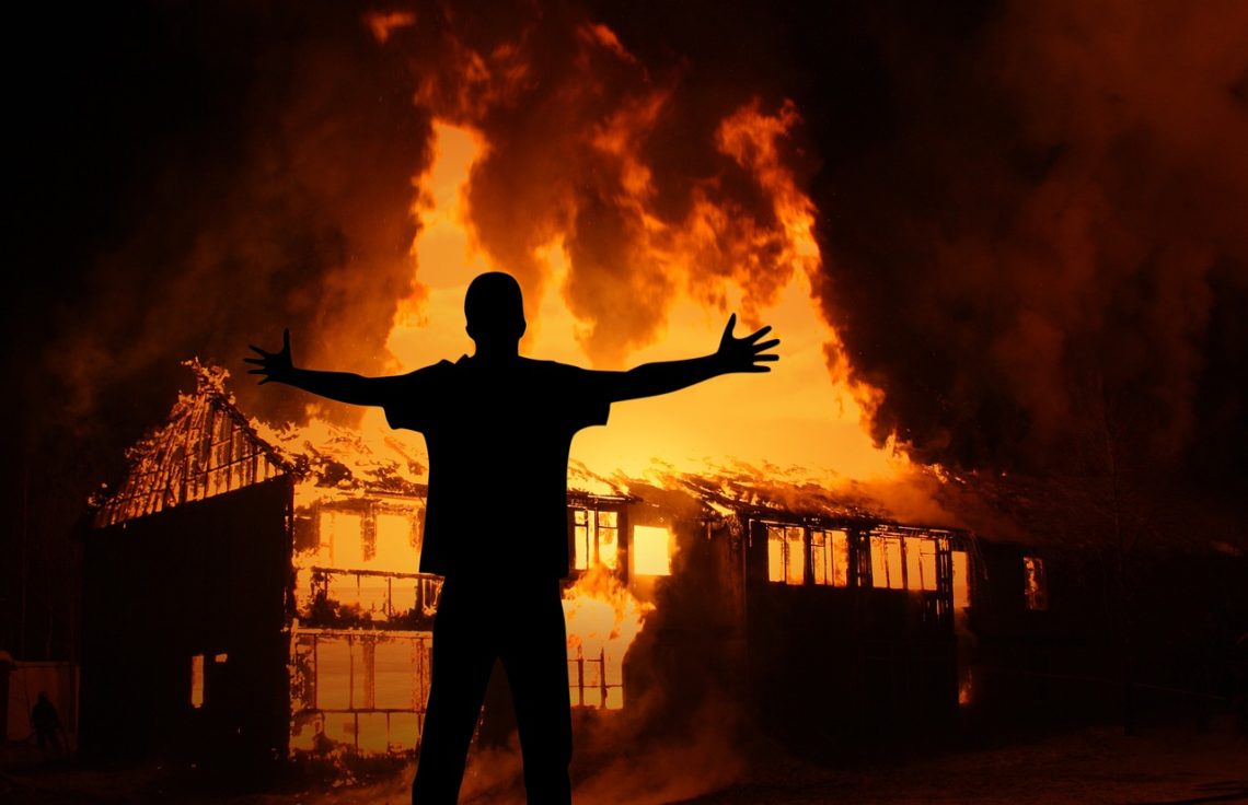 Man standing infront of burning building